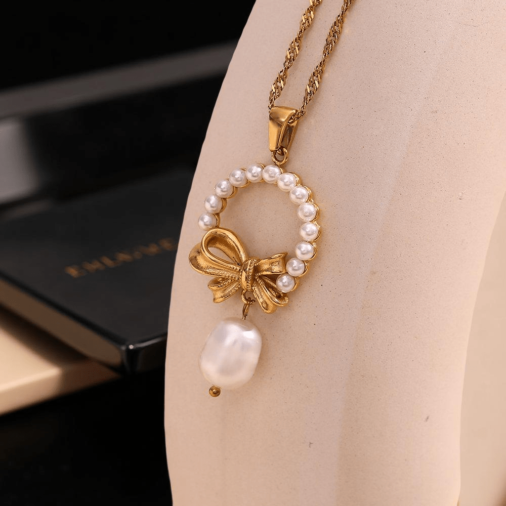 Колието от стомана Нора се отличава с красив съвременен дизайн.Висулката е във формата на кръг с панделка и перлен детайл.